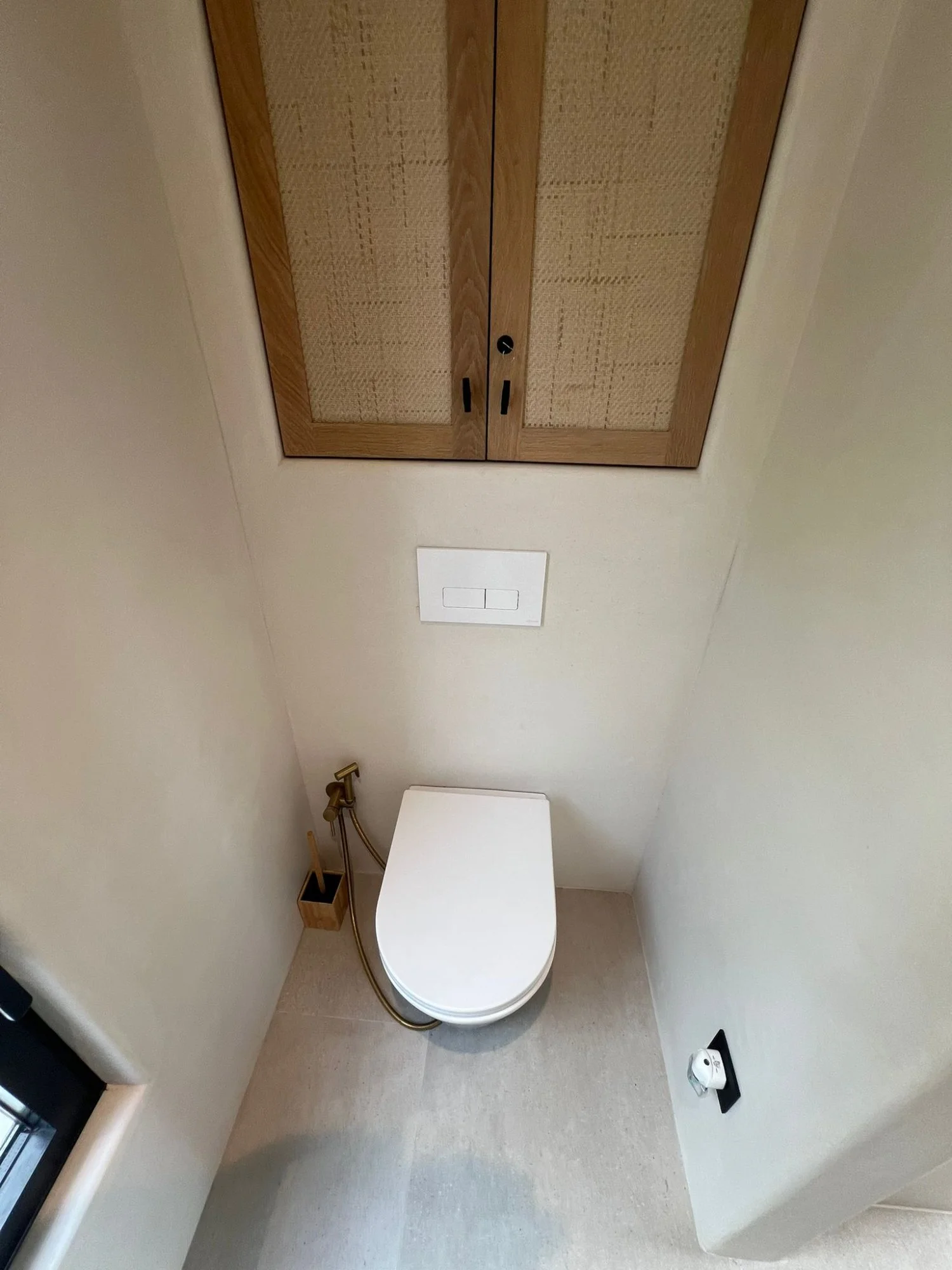 Baño reformado con inodoro suspendido y madera ratán en Ibiza